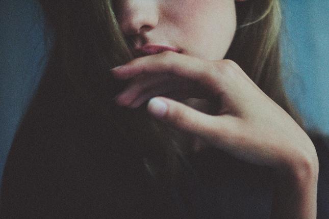 Dudas e inseguridad cuando falta asertividad Primer plano de la mano de una mujer junto a su boca, transmitiendo duda e inseguridad a la hora de expresar lo que siente por falta de asertividad.