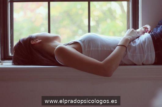 Persona recostada junto a una ventana en una escena de introspecci&oacute;n