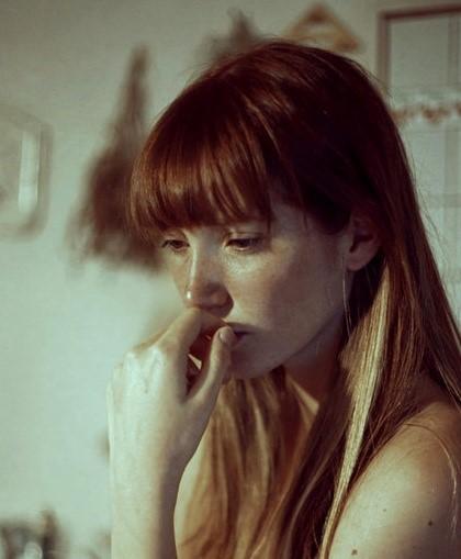 Joven pensativa con la mano en la boca en una cocina, simbolizando la preocupación constante y la comparación social asociadas al FOMO