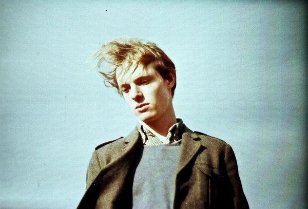 Joven mirando hacia abajo con gesto pensativo frente a un cielo despejado, reflejando ansiedad y sensación de FOMO