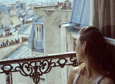 Mujer sentada junto a una ventana, mirando la ciudad con actitud reflexiva, simbolizando la necesidad de parar y desconectar del FOMO