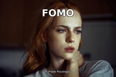 Mujer pelirroja con expresión preocupada y la mano en el cuello, reflejando ansiedad y preocupación por el FOMO y las redes sociales