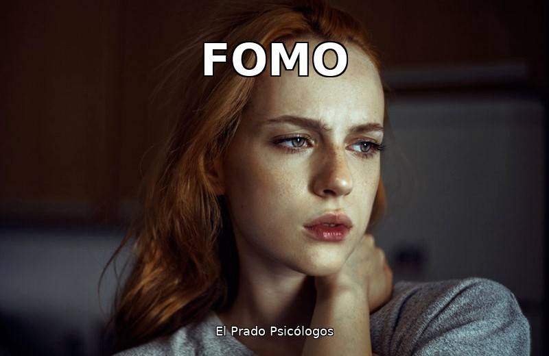 Mujer pelirroja con expresión preocupada y la mano en el cuello, reflejando ansiedad y preocupación por el FOMO y las redes sociales