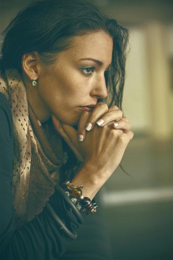 Mujer morena con las manos entrelazadas frente al rostro y mirada seria, valorando pedir ayuda psicológica para manejar el FOMO