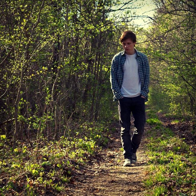 Joven caminando solo por un sendero en el bosque